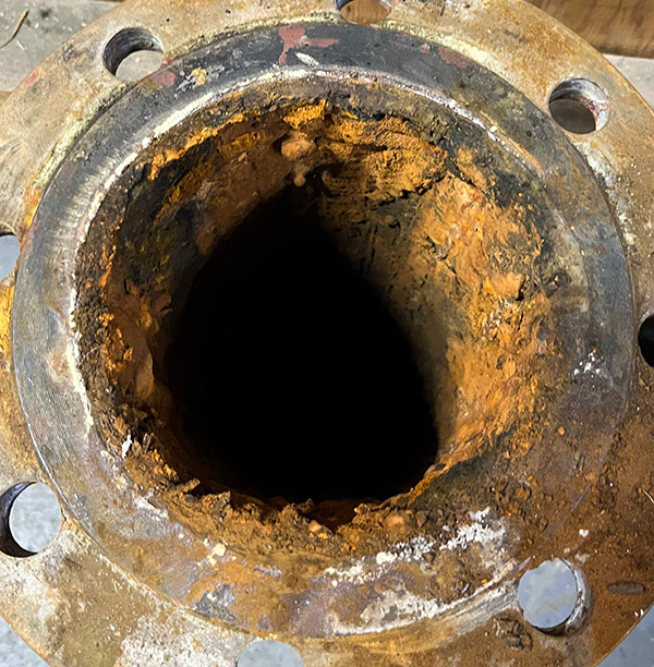 A flanged steel pipe showing build up of deposits and narrowing of the bore A flanged steel pipe showing build up of deposits and narrowing of the bore